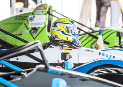 A driver wearing a safety helmet sitting in a racecar