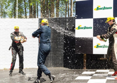 Three drivers celebrating a race victory by dousing each other with Champagne