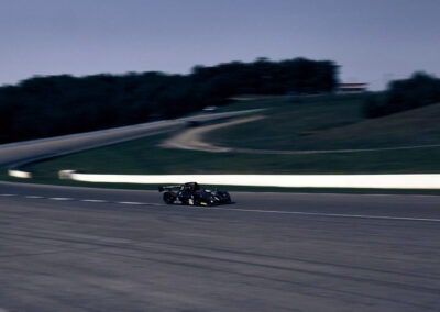 A wide shot of Team Earle’s #39 Radical SR3 XX, painted black, in motion, driving down an otherwise empty track