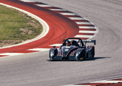 Team Earle’s #39 Radical SR3 XX, painted black and taking a turn on an otherwise empty motor speedway