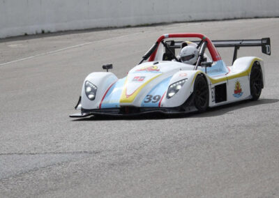 Team Earle’s #39 Radical SR3 XX, painted white, blue, and yellow, and cruising down an otherwise empty race track