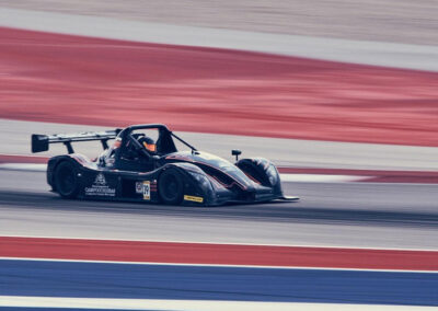 Team Earle’s #39 Radical SR3 XX, painted black and in motion on a red, white, and blue race track