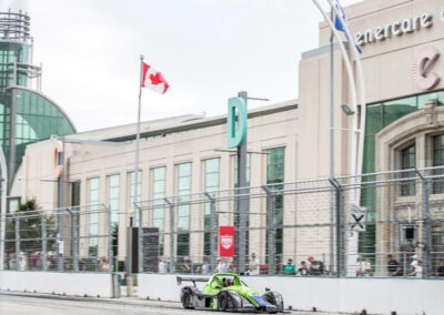Team Earle’s #39 Radical SR3 XX, painted green, racing down a road lined with spectators
