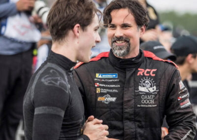 Daniel Earle, captain of Team Earle and president and CEO of Highlander Silver, in racing fatigues speaking with another team member